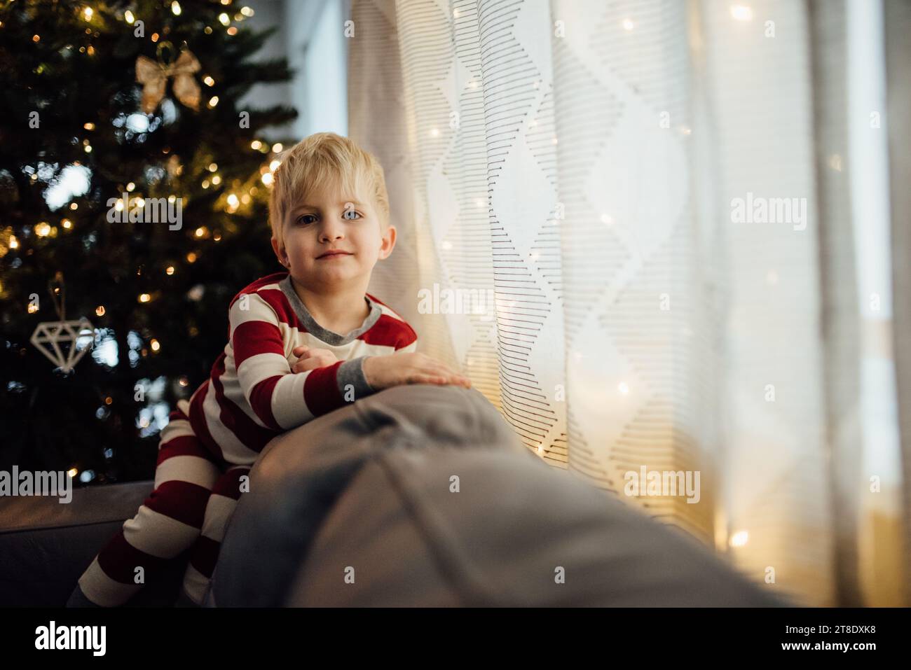 Un bambino che indossa un pigiama natalizio sorride davanti alla macchina fotografica Foto Stock