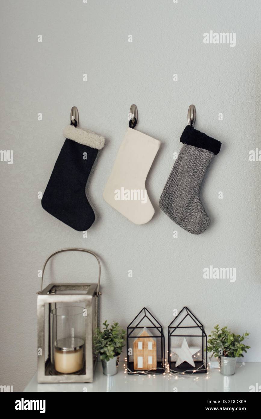 3 calze in stile appese su un muro sopra il decoro natalizio Foto Stock