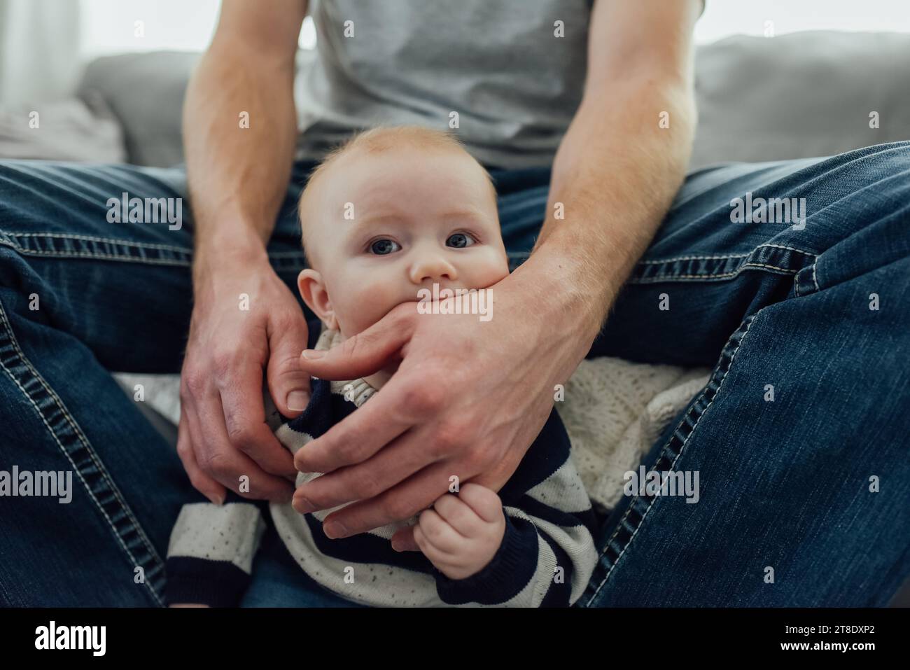 Primo piano del bambino che masticava la mano di papà mentre teneva la sua pinna Foto Stock