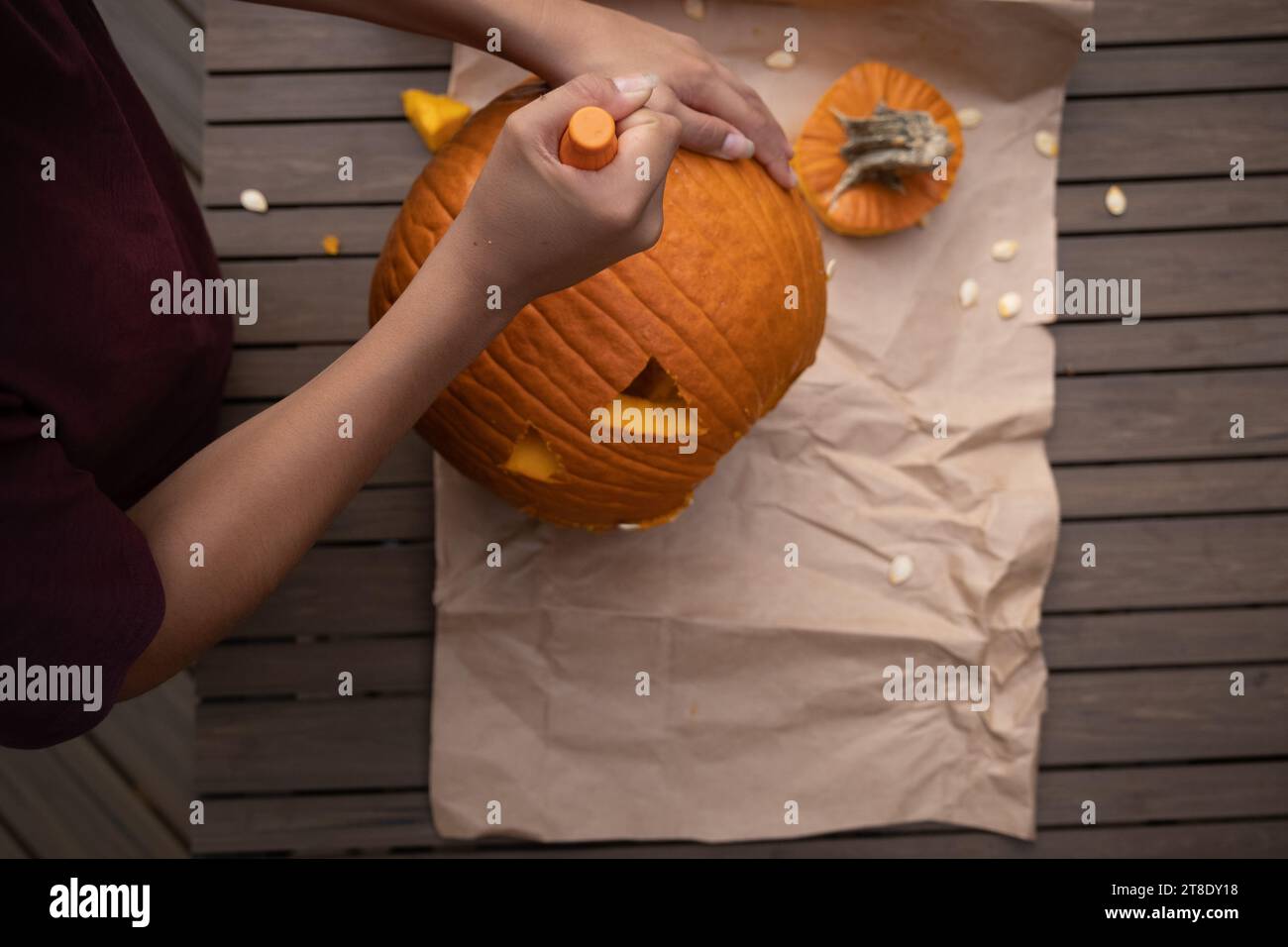 Bambini che intagliano la zucca arancione sul tavolo all'aperto prima di Halloween. Foto Stock