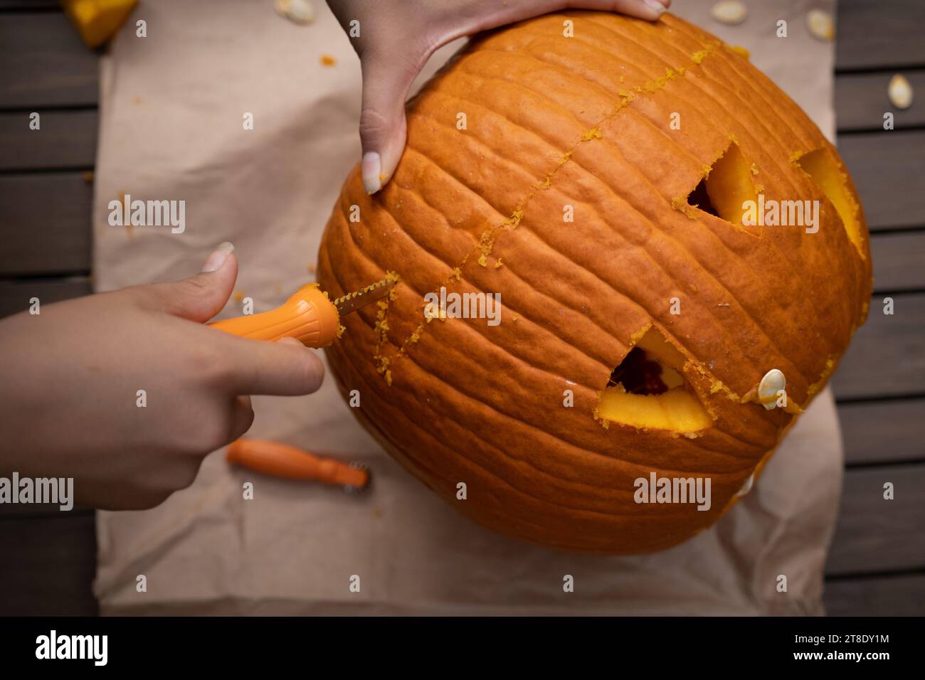 Bambini che intagliano la zucca arancione sul tavolo all'aperto prima di Halloween. Foto Stock