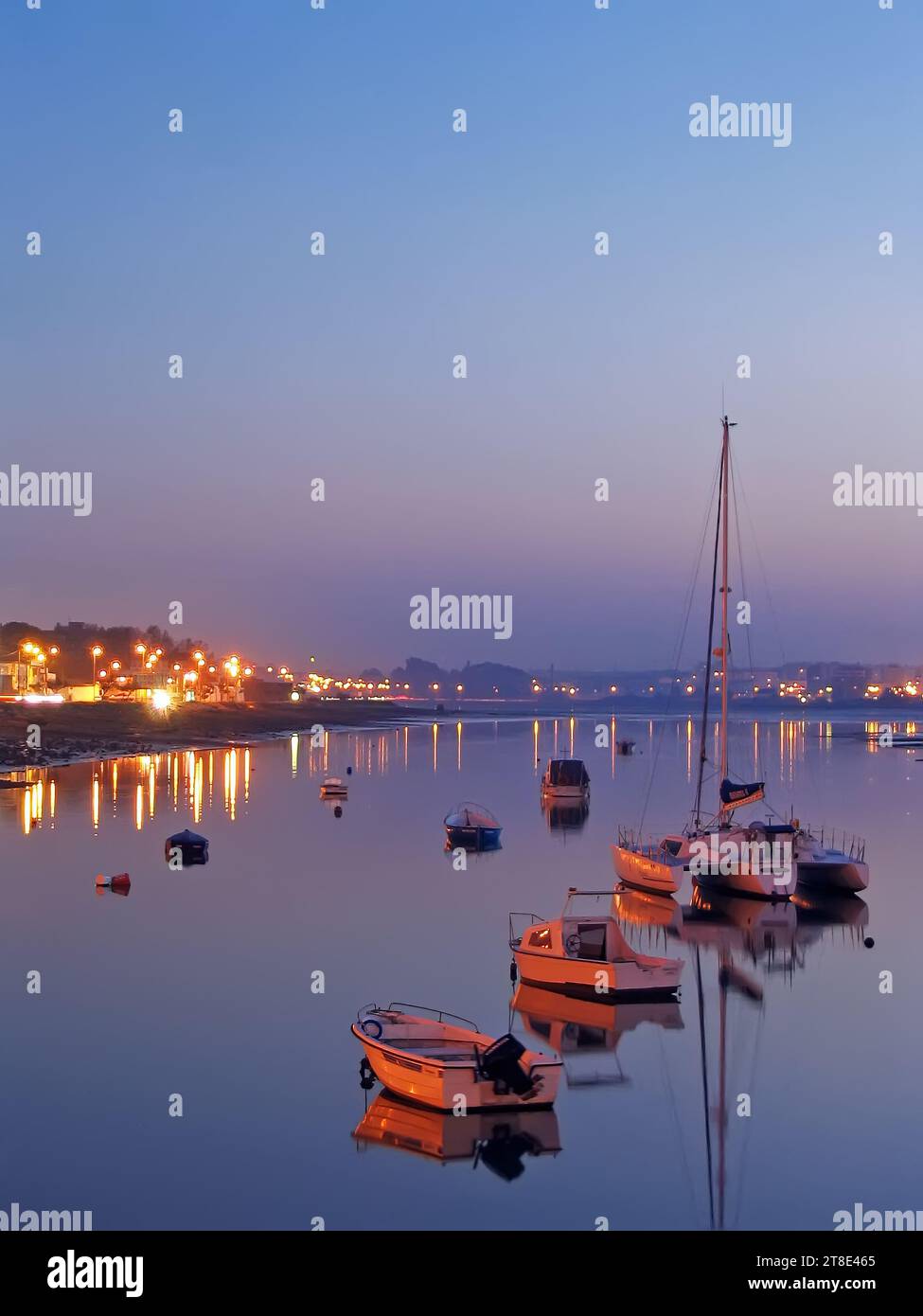 Baia di Seixal con piccole barche e un trimarano a vela al crepuscolo, al tramonto o alla sera. Setubal, Portogallo Foto Stock