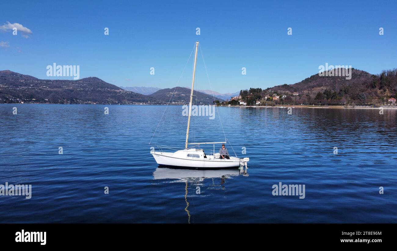 Barca a vela in Italia, Lombardia, Angera sul Lago maggiore; sullo sfondo le montagne Foto Stock