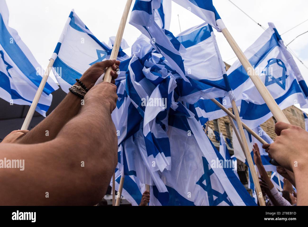 Un gruppo energico di giovani israeliani sventola bandiere bianche e blu dello Stato di Israele durante una parata per celebrare la giornata di Gerusalemme in Israele. Foto Stock