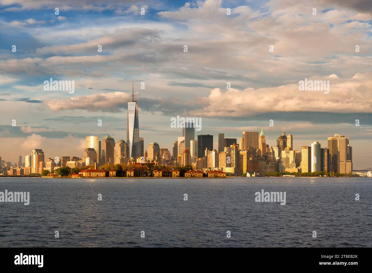 Vista del porto di New York dei grattacieli del quartiere finanziario di Lower Manhattan e di Ellis Island bagnata dalla luce del sole del tardo pomeriggio. Skyline di New York Foto Stock