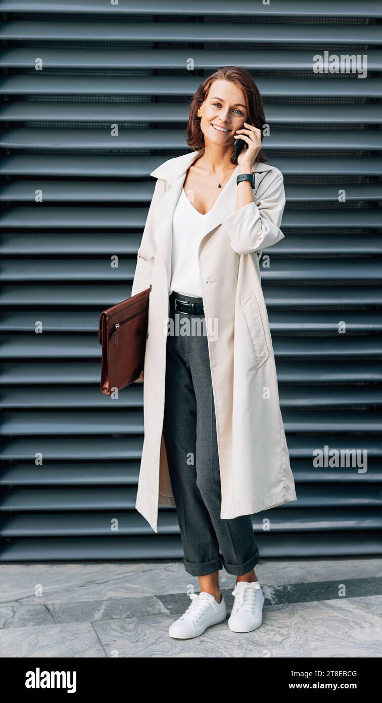 Elegante donna di mezza età che indossa un cappotto che parla al telefono cellulare Foto Stock