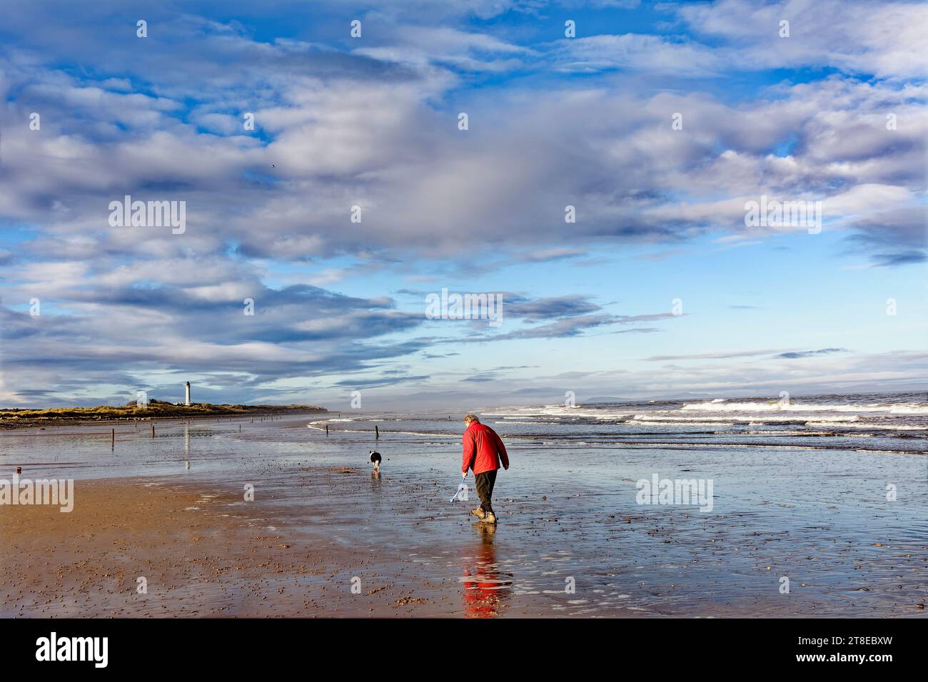 Lossiemouth Moray Coast Scozia la West Beach, il cielo e il mare di novembre, il camminatore e il suo cane sulla sabbia Foto Stock