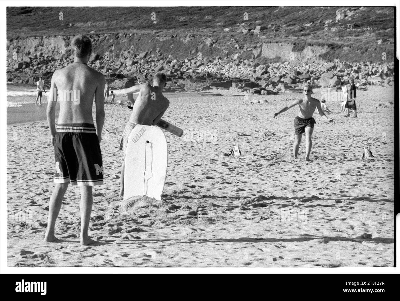 Gli adolescenti giocano a cricket sulla splendida spiaggia sabbiosa di Gwynver Beach a Sennen con una tavola da surf come i ceppi in Cornovaglia, Inghilterra, agosto 2000. Foto: ROB WATKINS Foto Stock