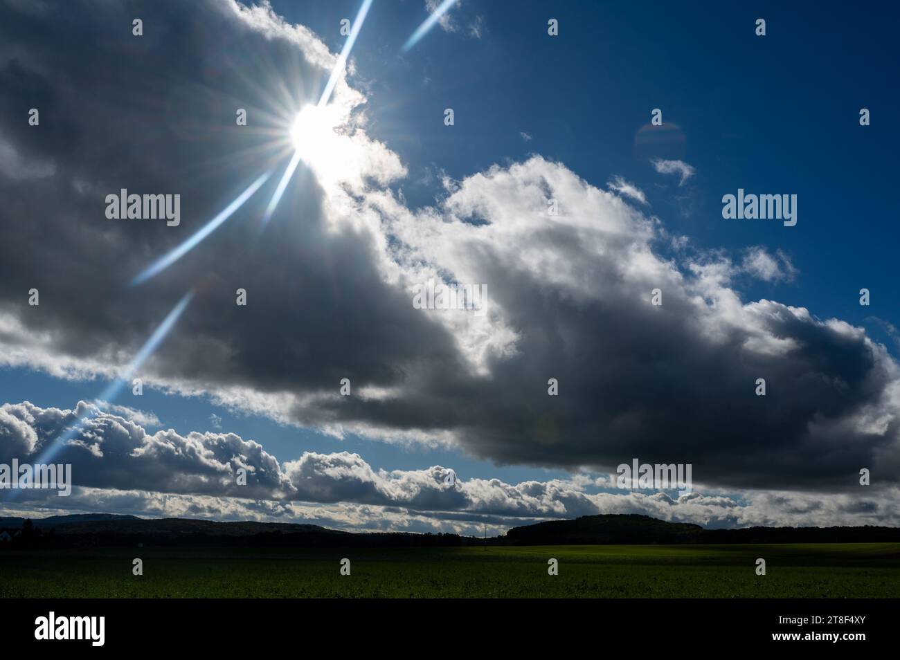 Le nuvole scure si uniscono con il sole e il paesaggio verde Foto Stock