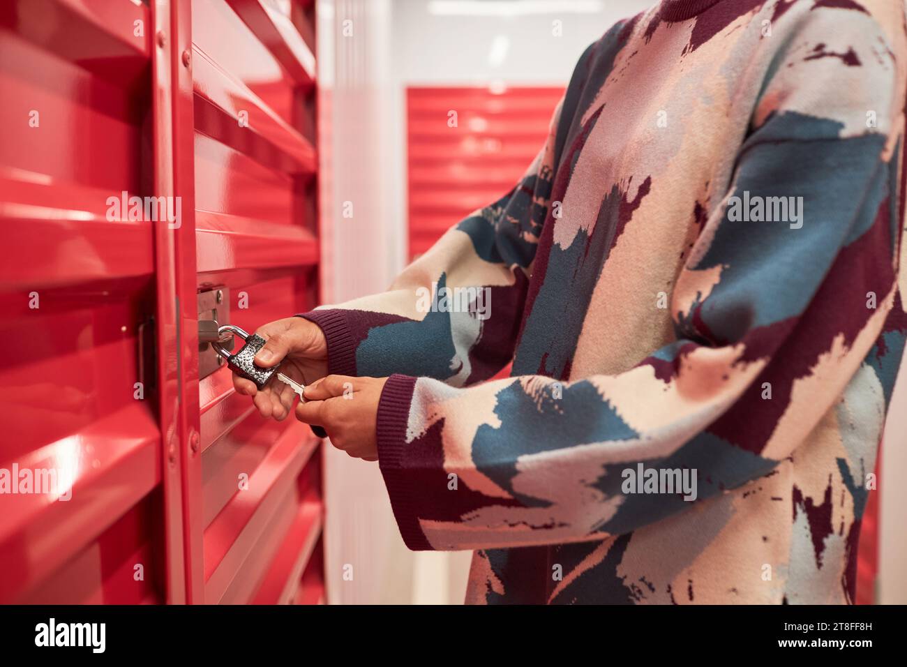 Immagine ritagliata di una giovane donna che apre la serratura sulla porta dell'unità di deposito auto Foto Stock