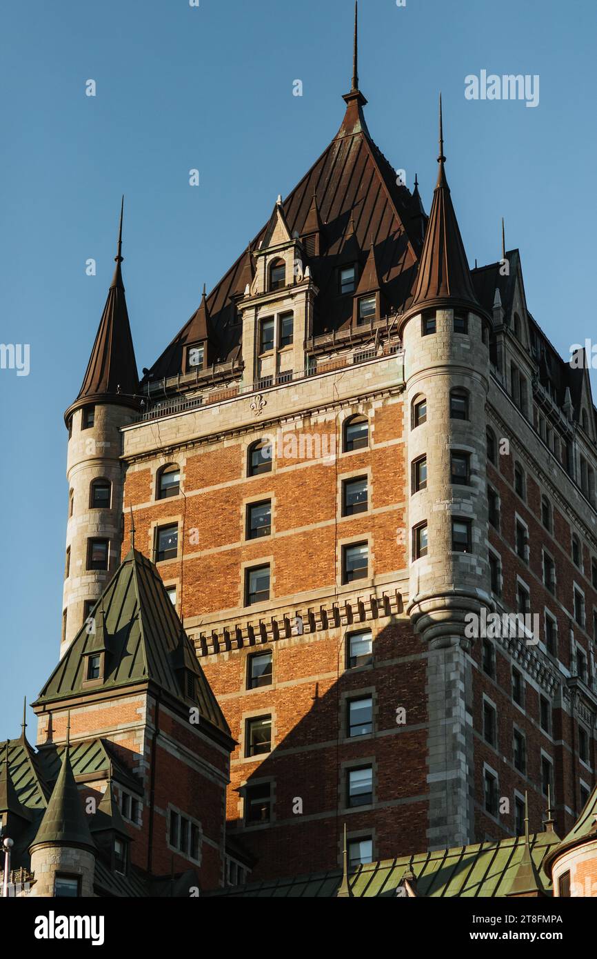 La luce del sole bagna l'architettura distintiva di un grande hotel in stile castello con torrette e guglie contro un vivace cielo blu in Quebec, Canada Foto Stock