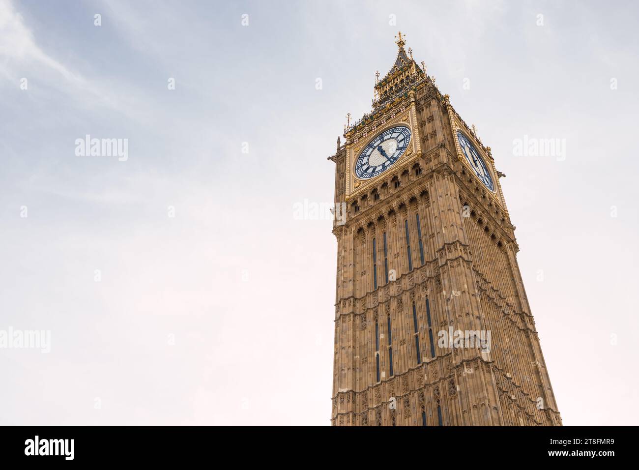Una vista chiara della storica torre dell'orologio del Big Ben, che si erge alto contro un cielo nuvoloso e chiaro sullo sfondo di Londra, offre un senso di luogo e tempo. Foto Stock