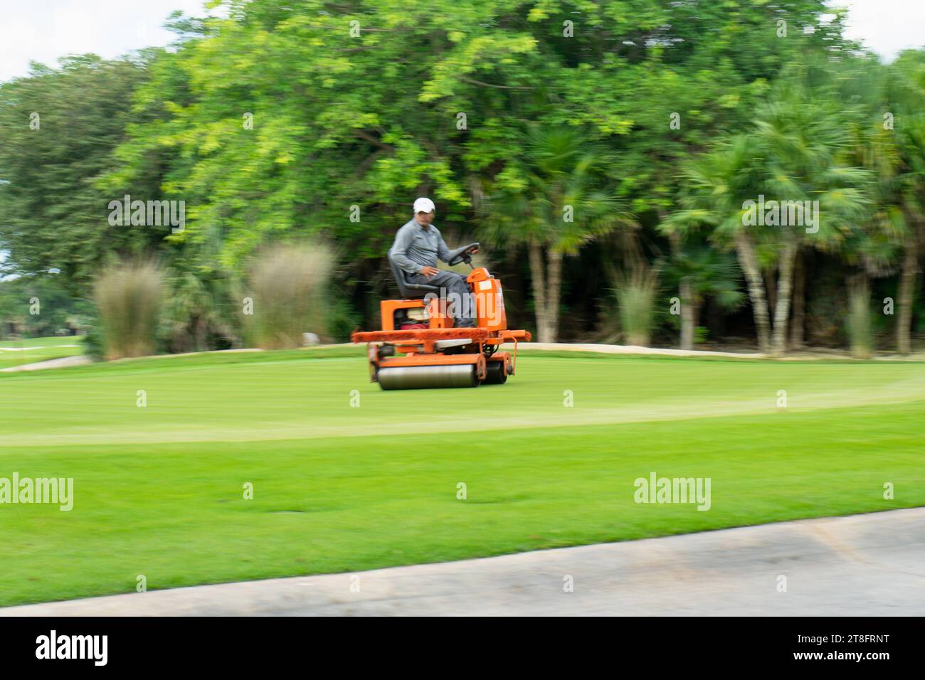 Immagine sfocata e in movimento di un giardiniere, mentre in Messico si esegue la manutenzione di un campo da golf con macchinari speciali Foto Stock