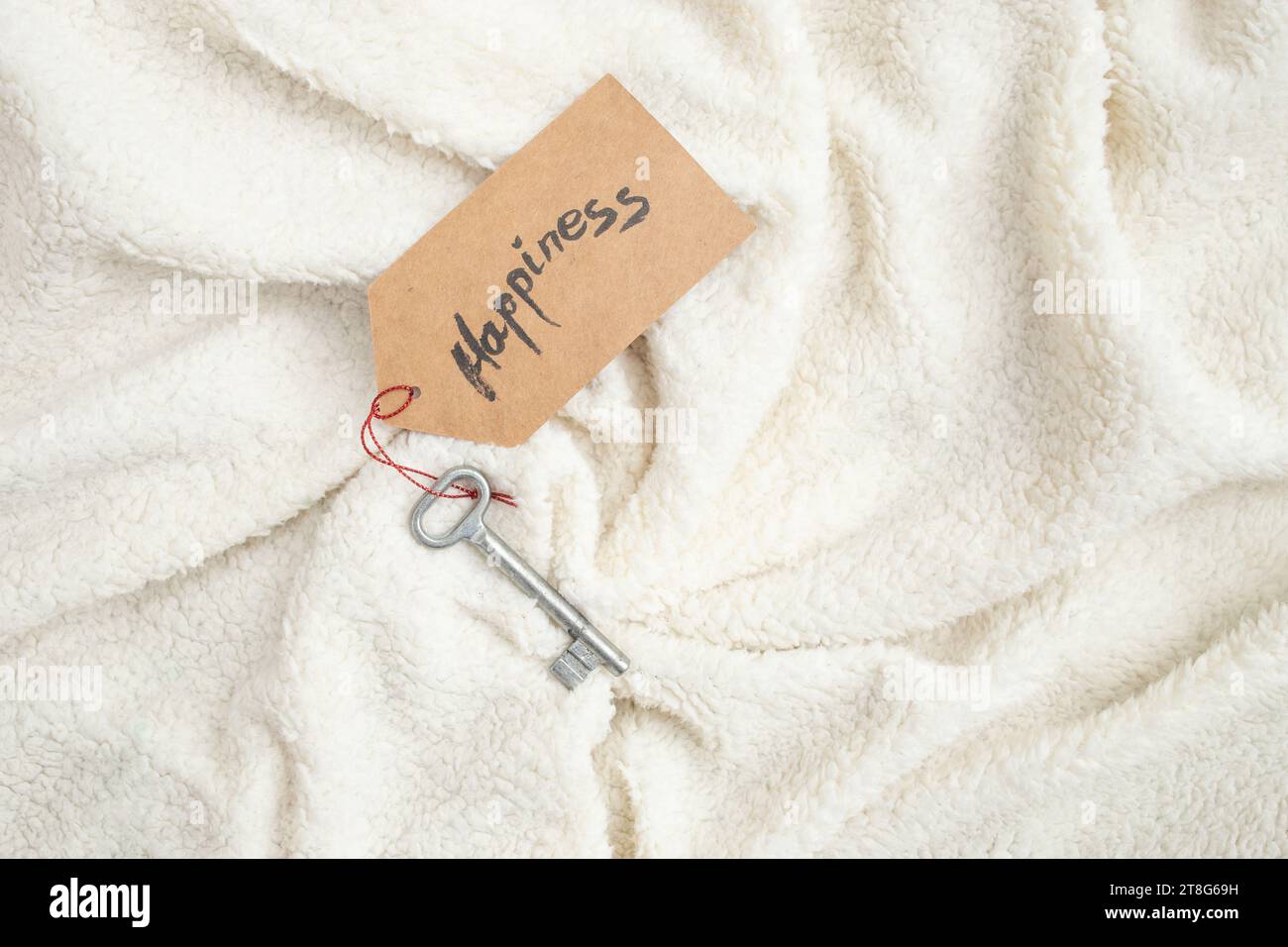 Parola di felicità, scritta a mano su un portachiavi di prezzo, su una coperta di peloso morbido, spianata Foto Stock