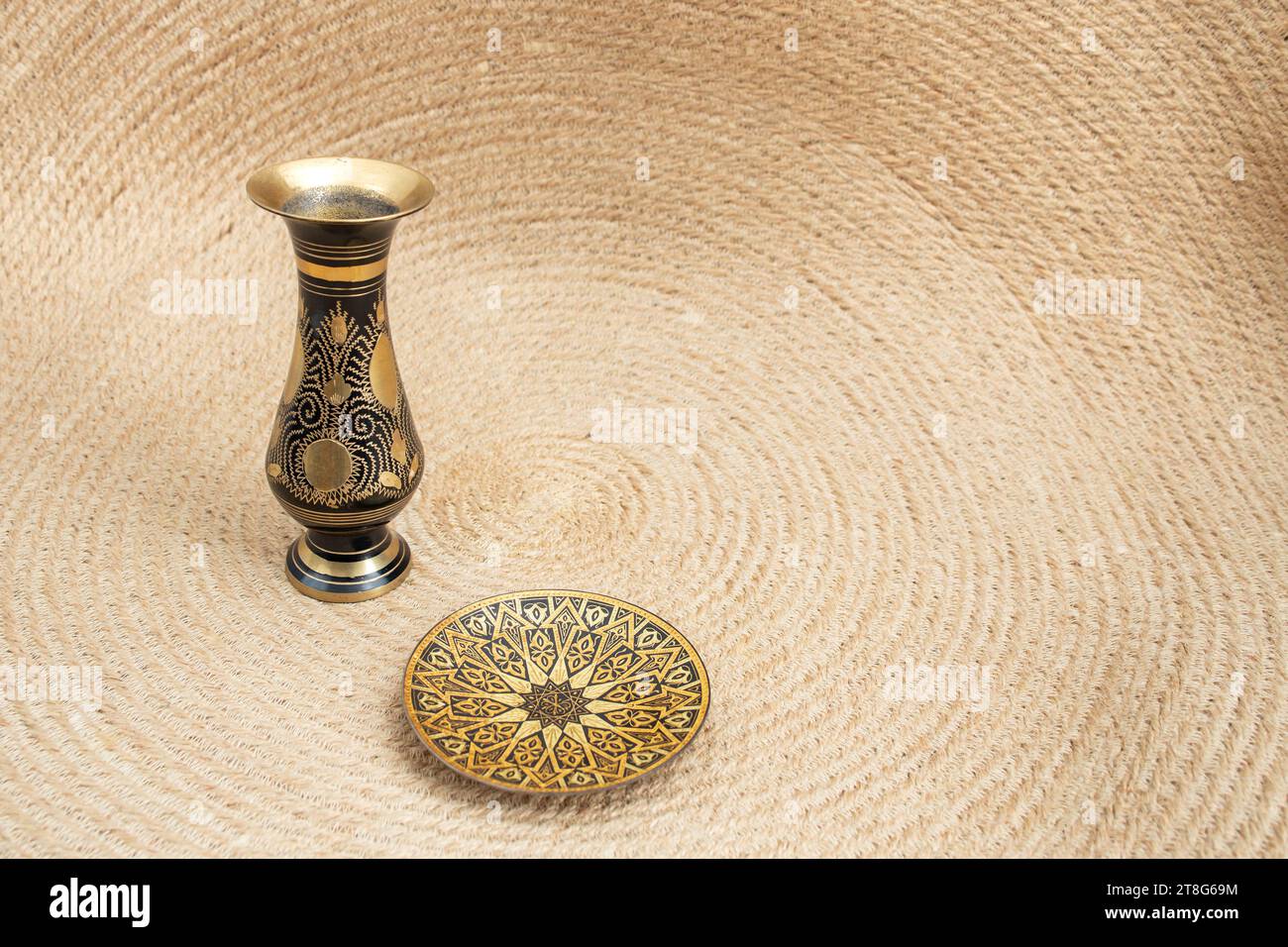 Sfondo bohémien con vaso decorativo in ottone su un tappeto in corda di iuta, vista laterale Foto Stock