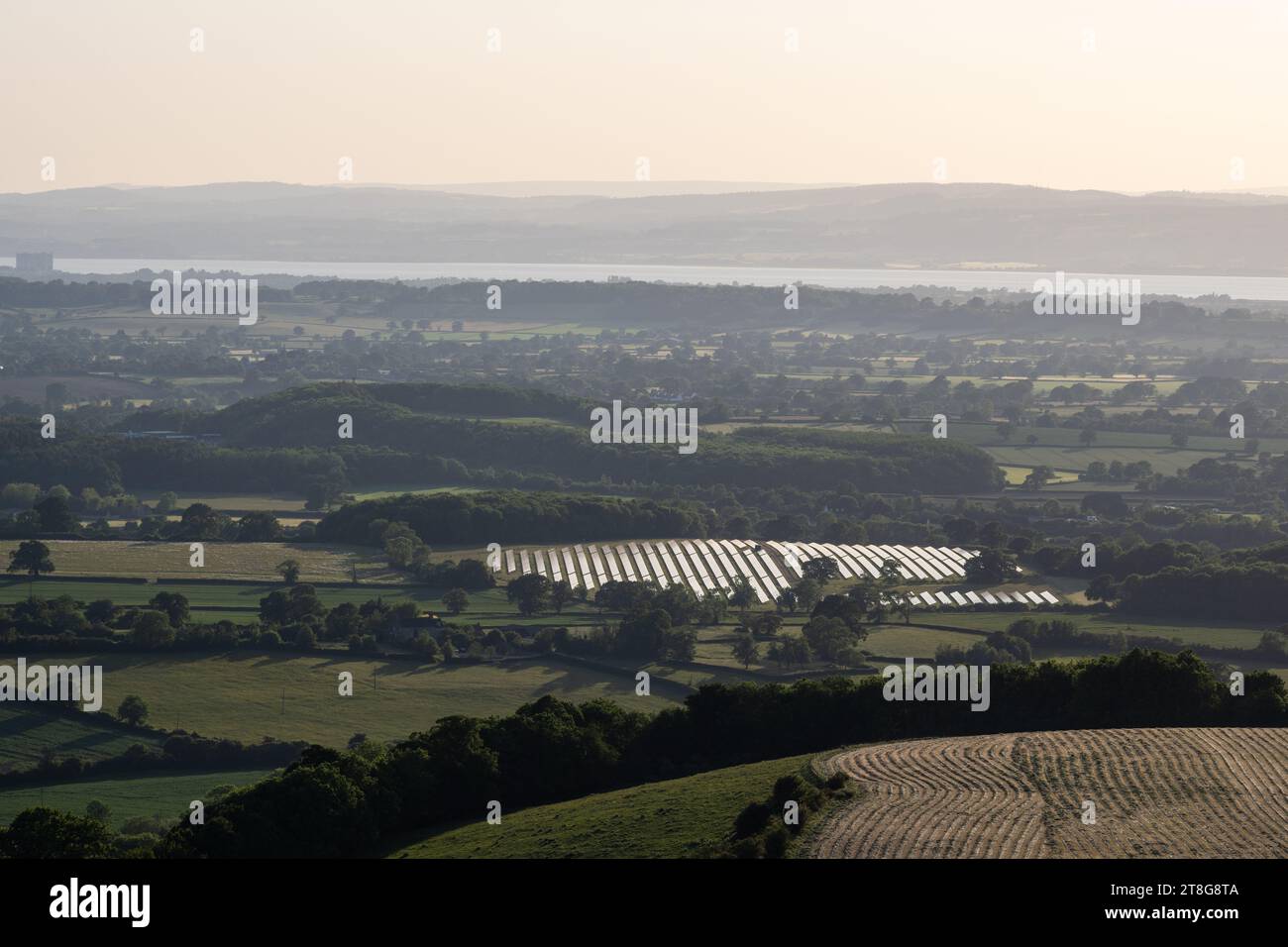 I campi di pannelli solari si trovano accanto all'autostrada M5 a Michael Wood nella campagna del Gloucestershire, con l'estuario del Severn e la Foresta di Dean Foto Stock