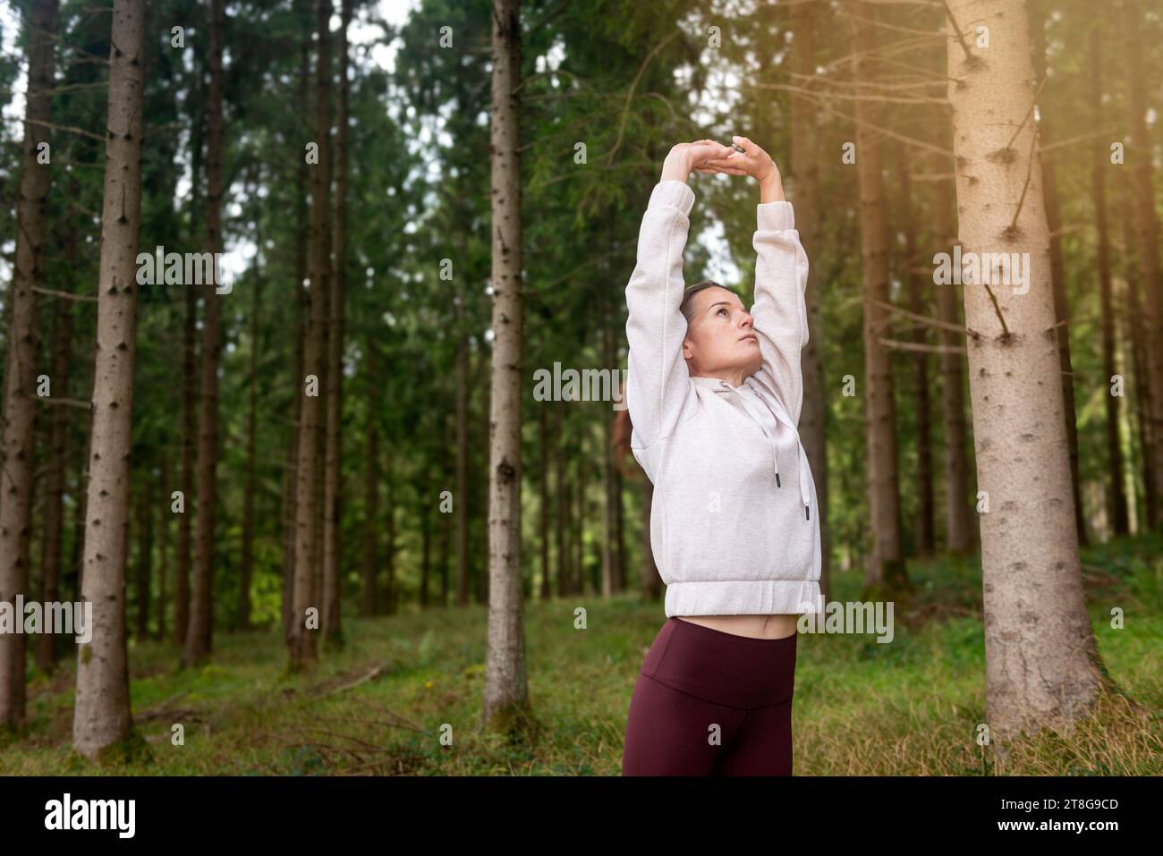 donna sportiva in forma che fa esercizio di stretching nella foresta, esercizi di riscaldamento. Foto Stock
