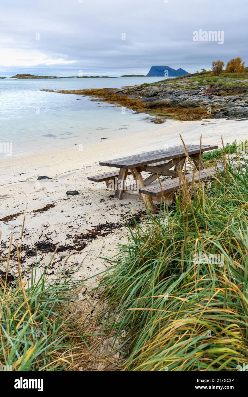 Area barbecue sulla costa atlantica vicino a Sommarøy, Norvegia. Spiaggia sabbiosa con grill, panca del parco e area relax, vicino al mare turchese come i caribici Foto Stock