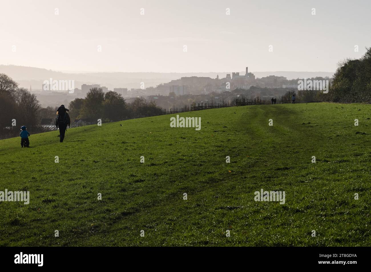 La gente cammina attraverso lo Stoke Park nella parte nord di Bristol, con lo skyline del centro città, Kingsdown, il St Michael's Hospital e l'Università di Bristol B. Foto Stock