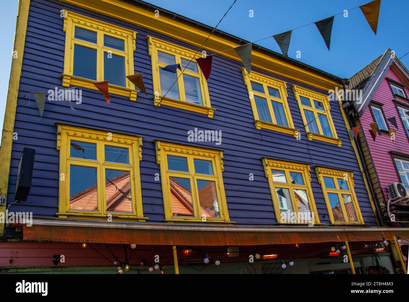 Stavanger, ventanas con sus reflejos en una de las casas de colores brillantes, azul y amarillo, en la calle Øvre Holmegate o Fargegaten, Noruega Foto Stock