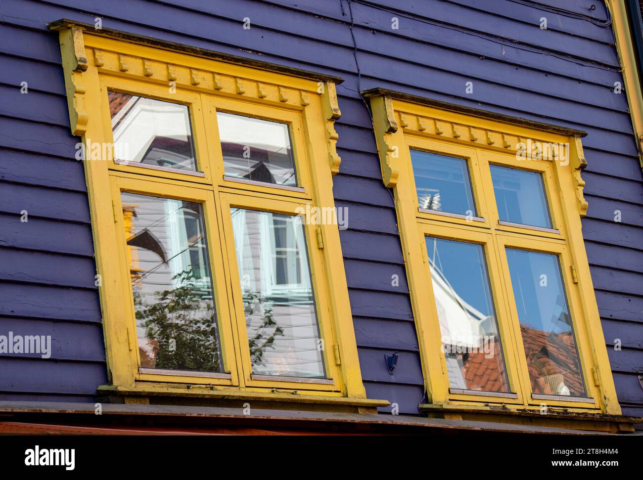 Stavanger, ventanas con sus reflejos en una de las casas de colores brillantes, azul y amarillo, en la calle Øvre Holmegate o Fargegaten, Noruega Foto Stock