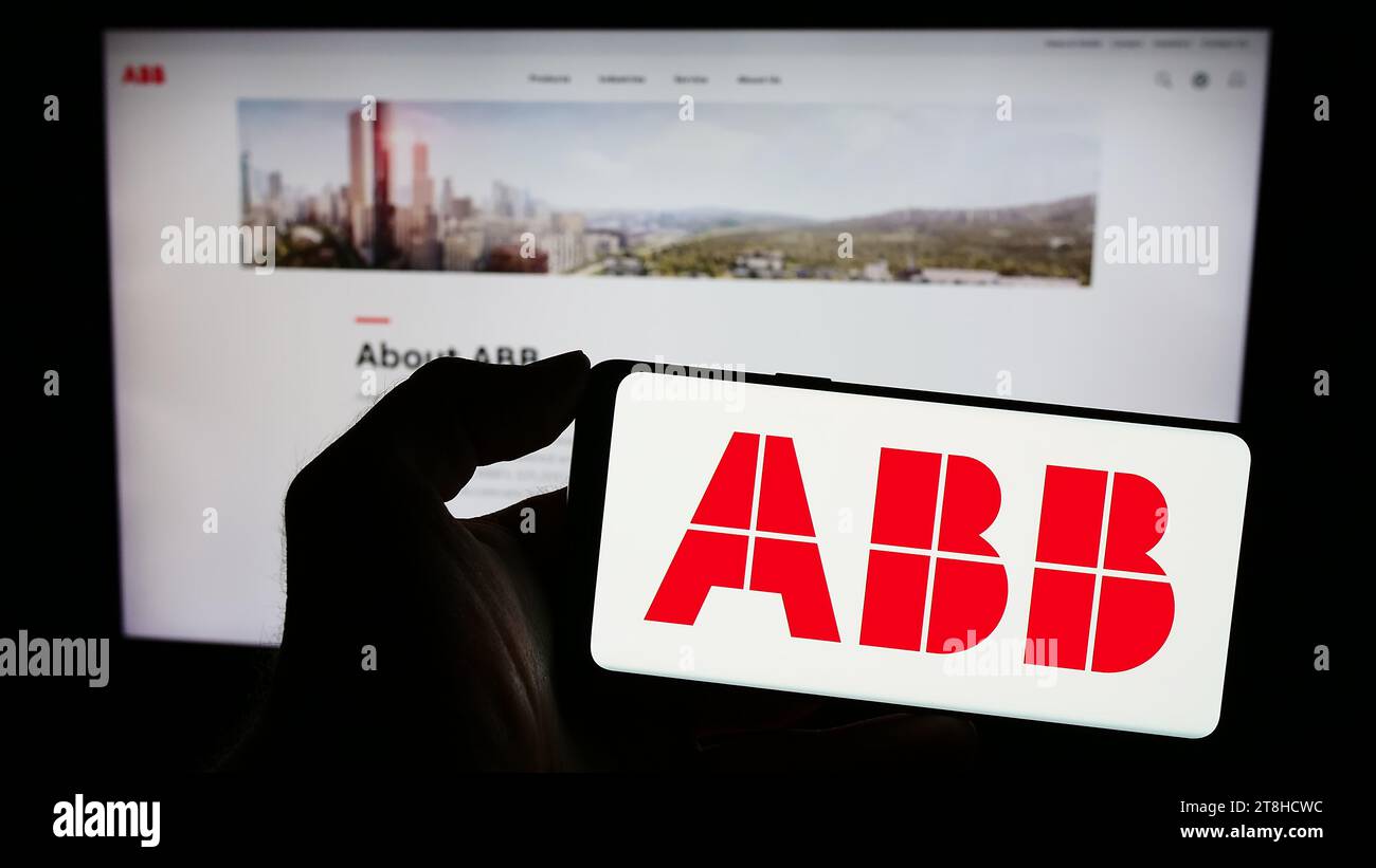 Persona che possiede uno smartphone con il logo dell'azienda di apparecchiature elettriche ABB Ltd. Davanti al sito Web. Concentrarsi sul display del telefono. Foto Stock