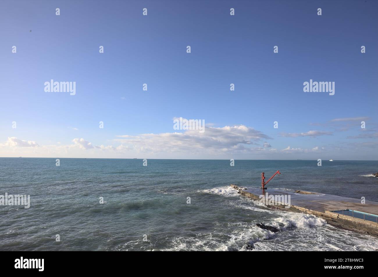 Gru rossa e una piattaforma vicino al frangiflutti al mare in una giornata di sole Foto Stock