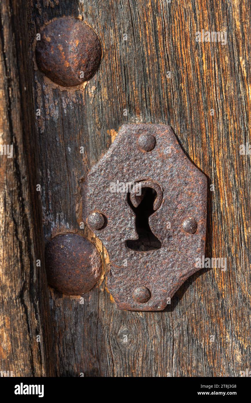 Antico buco metallico arrugginito sulla vecchia porta in legno, primo piano Foto Stock