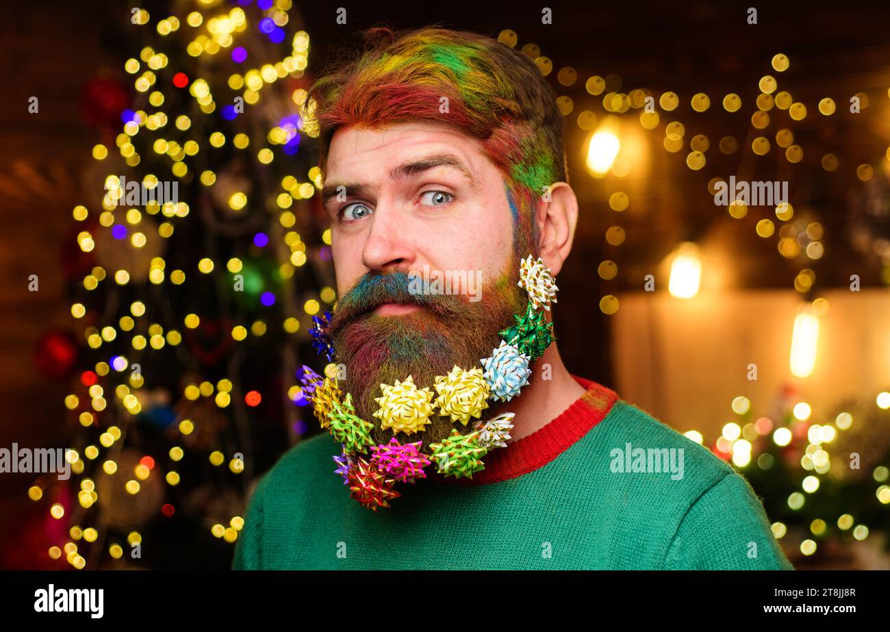 Uomo barbuto con barba decorata per la festa di Capodanno. Buon Natale. Buon anno nuovo. Barba di Natale. Uomo di Natale con capelli tinti e barba Foto Stock