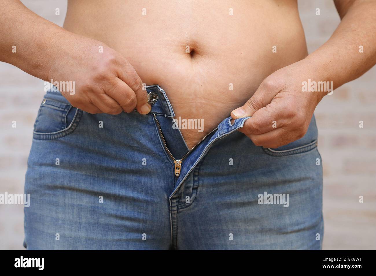 la moglie ha messo su peso e non riesce più a chiudere i suoi jeans Foto Stock