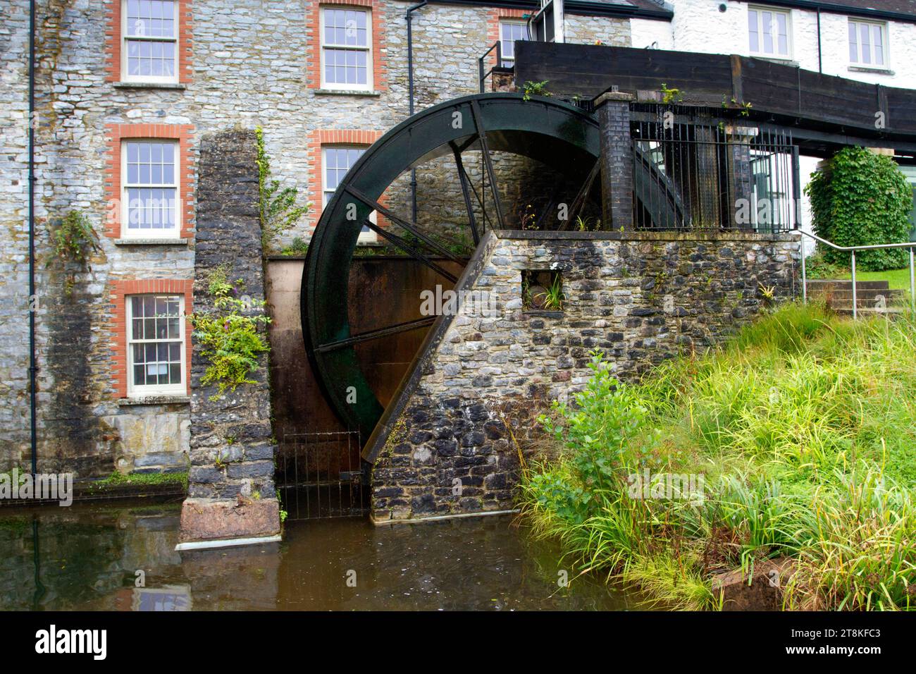 Una ruota idraulica a Higher Mill, Buckfast (adiacente all'abbazia di Buckfast) nel Devon, Inghilterra, che genera energia idroelettrica. Foto Stock
