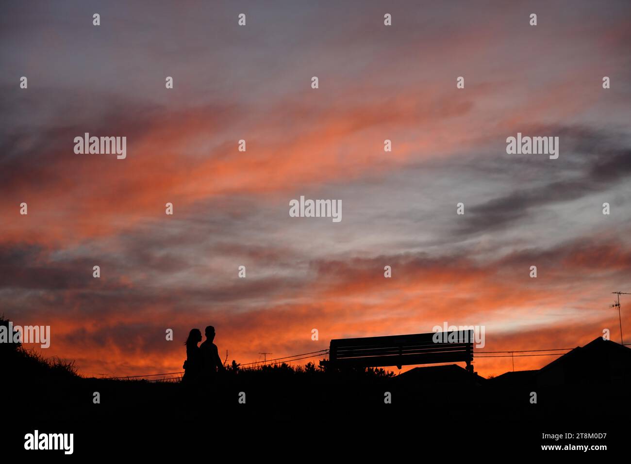 Una coppia si staglia contro un tramonto arancione sopra Maroubra Beach Sydney. Foto Stock