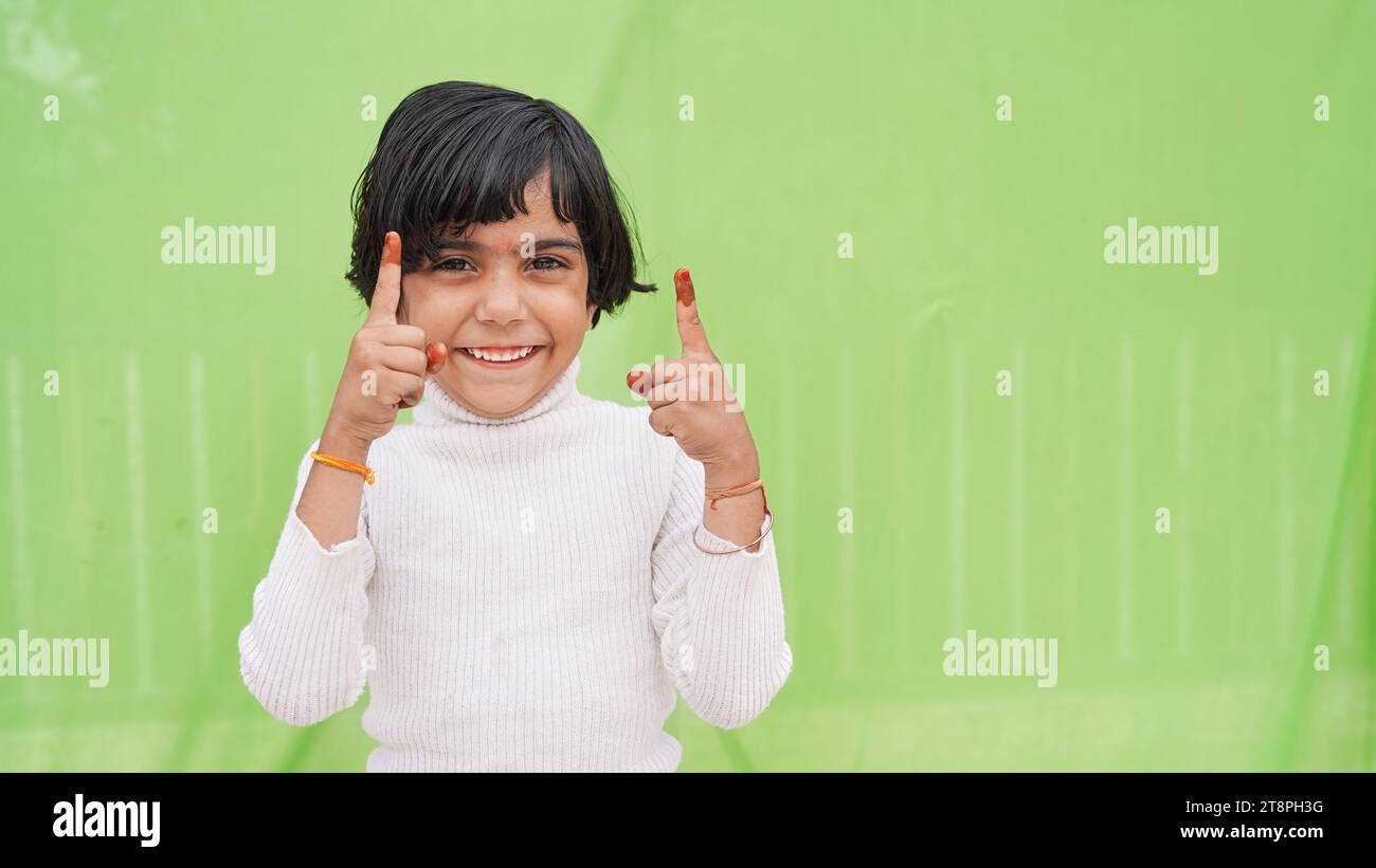 Foto di una bambina allegra che guarda le dita dirette sullo spazio vuoto promo isolato su sfondo verde Foto Stock