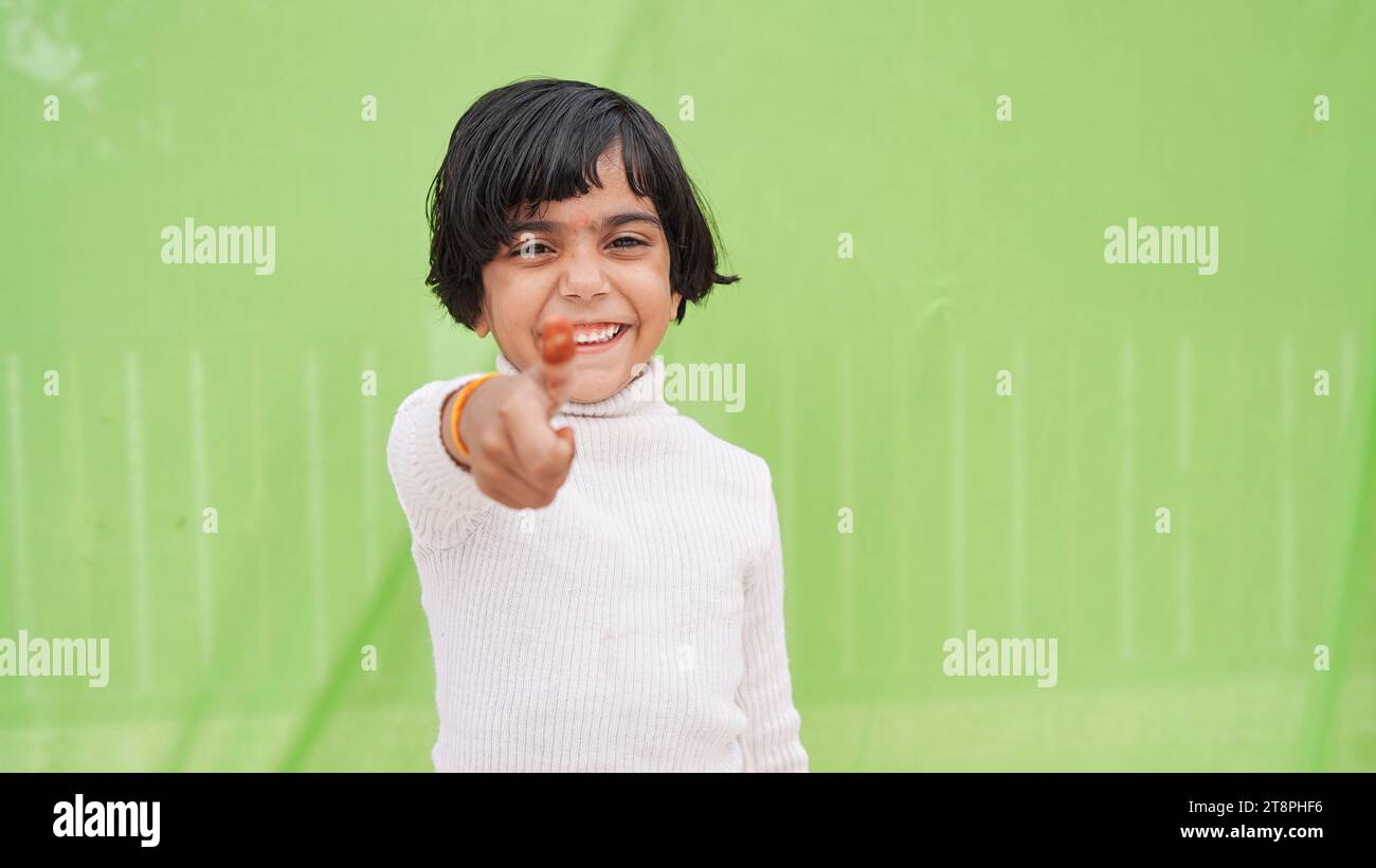 Bambina felice e positiva con dolcevita bianca che mostra il pollice in alto come un gesto isolato su un ritratto in studio di colore verde chiaro pastello. Foto Stock
