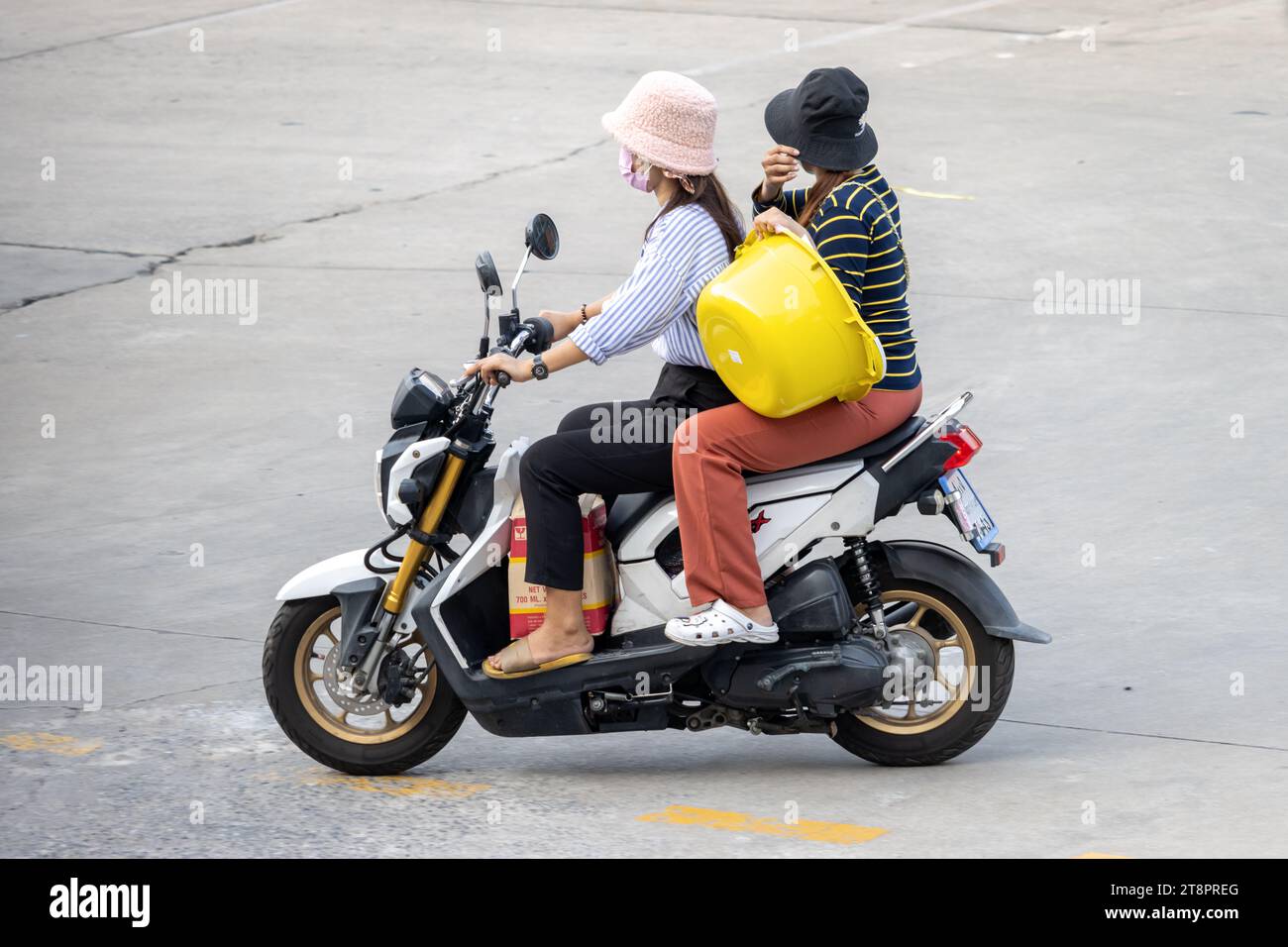 Due donne trasportano merci su una moto, Thailandia Foto Stock