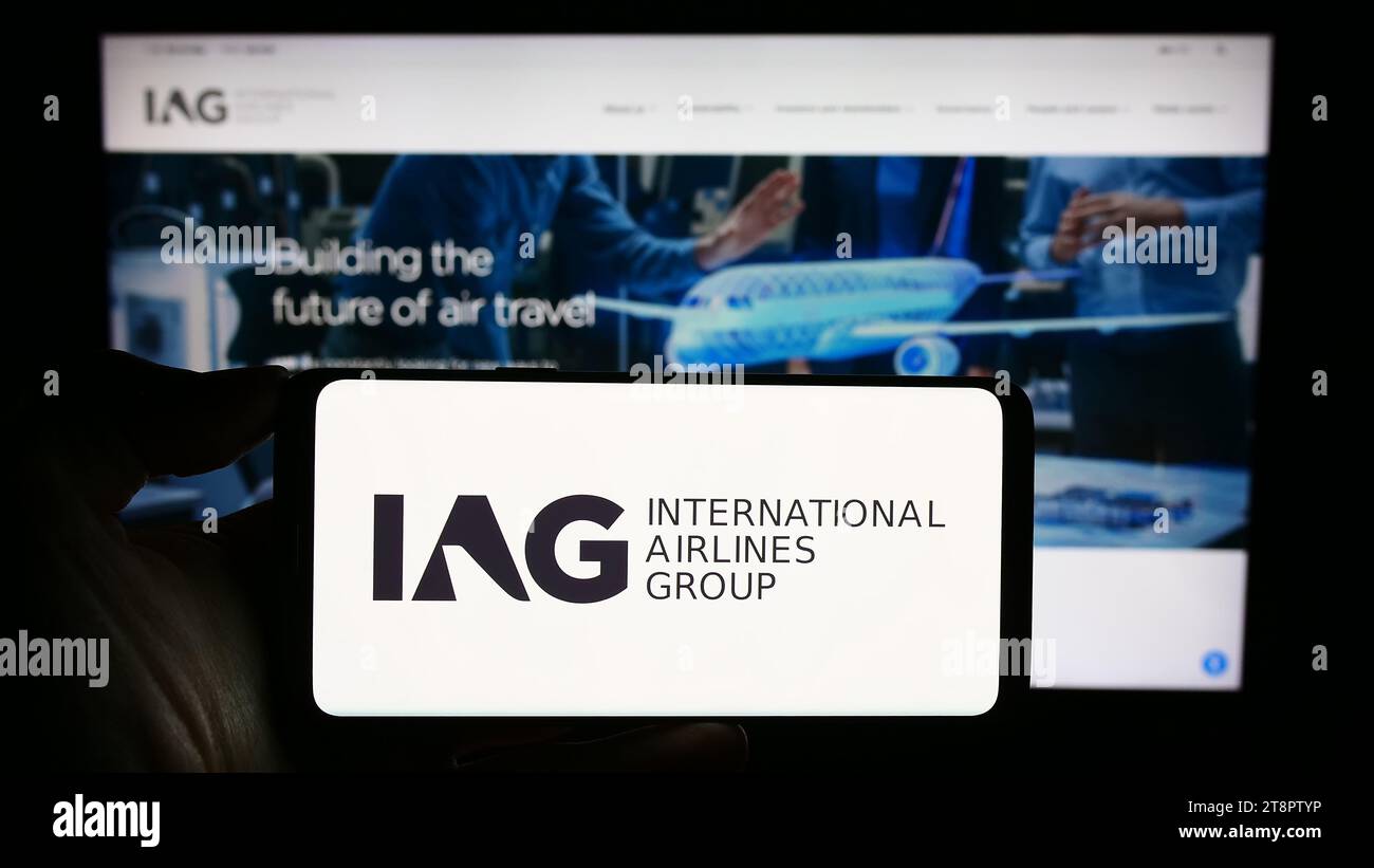 Persona che possiede uno smartphone con il logo di International Consolidated Airlines Group SA (IAG) davanti al sito Web. Concentrarsi sul display del telefono. Foto Stock