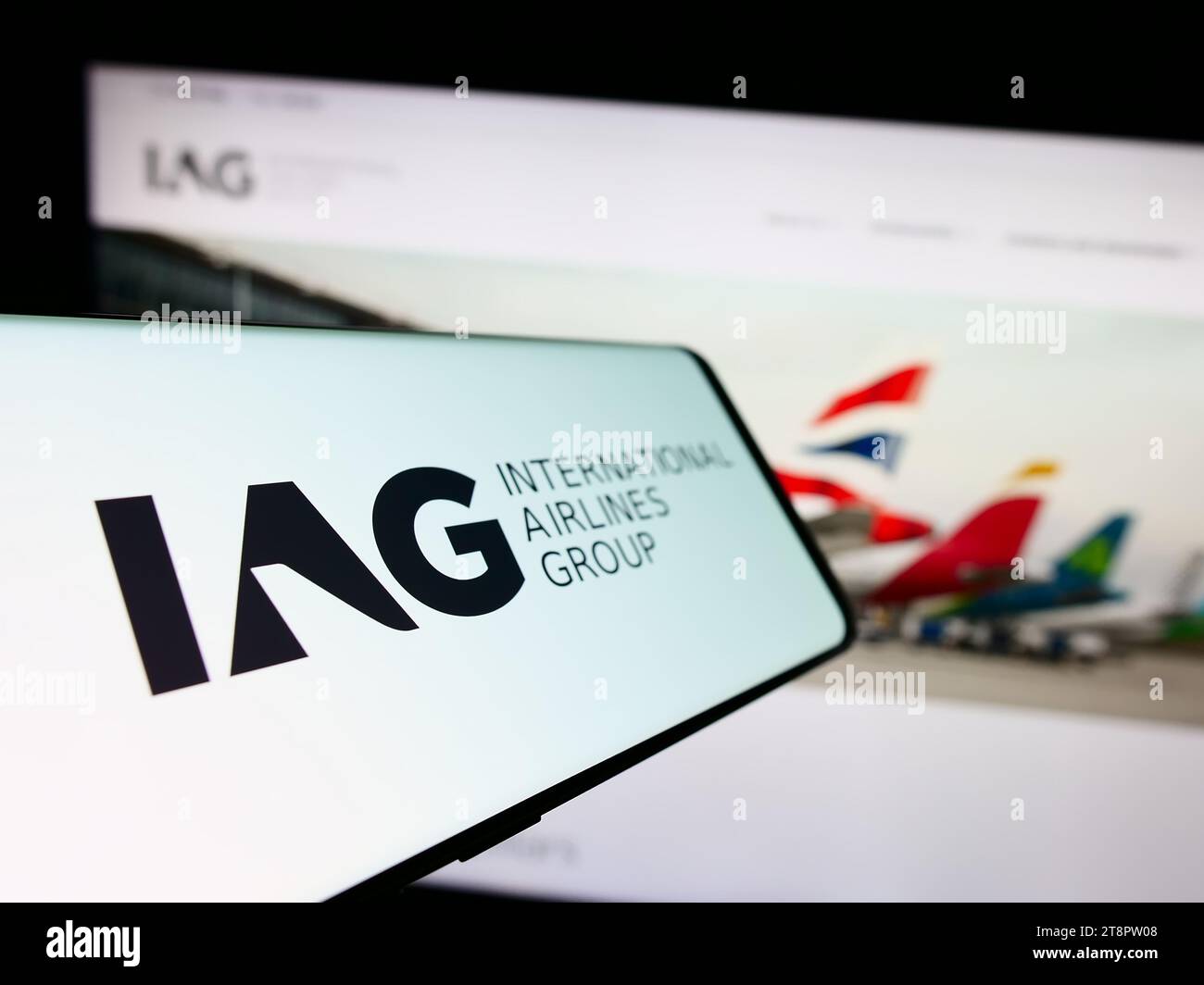 Smartphone con logo di International Consolidated Airlines Group SA (IAG) davanti al sito Web aziendale. Mettere a fuoco il display centrale sinistro del telefono. Foto Stock