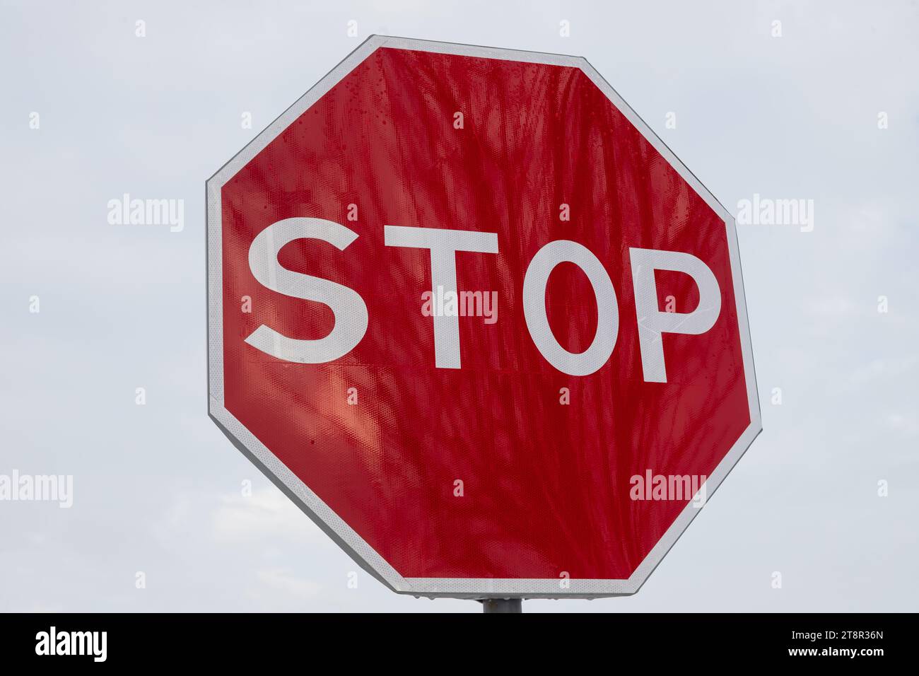 segnale di stop rosso sulla strada su sfondo nuvoloso. Segnale isolato. Foto Stock