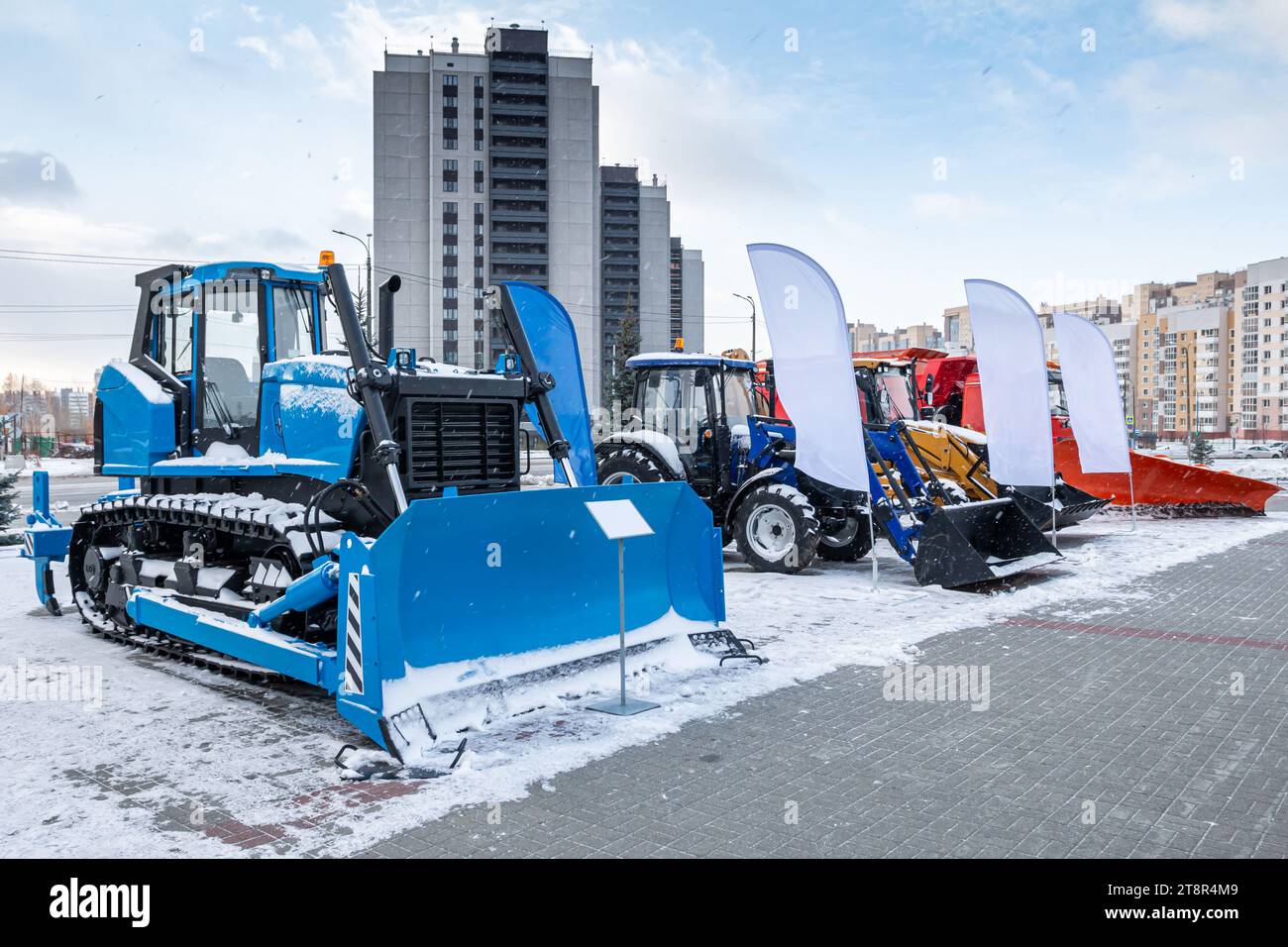 Apripista e trattori gommati con versoio in occasione di una fiera industriale invernale Foto Stock