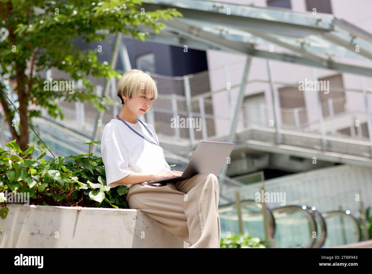 Giovane donna giapponese che lavora sul suo portatile nel centro di Tokyo Foto Stock