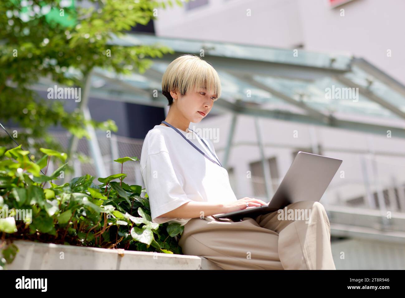 Giovane donna giapponese che lavora sul suo portatile nel centro di Tokyo Foto Stock