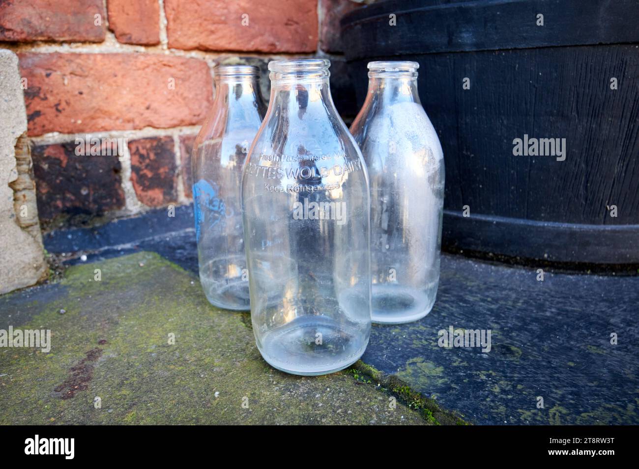 vecchie bottiglie di latte da pinta tradizionali del diario di cotteswold lasciate alle porte di una casa al mattino di ormskirk, lancashire, inghilterra, regno unito Foto Stock
