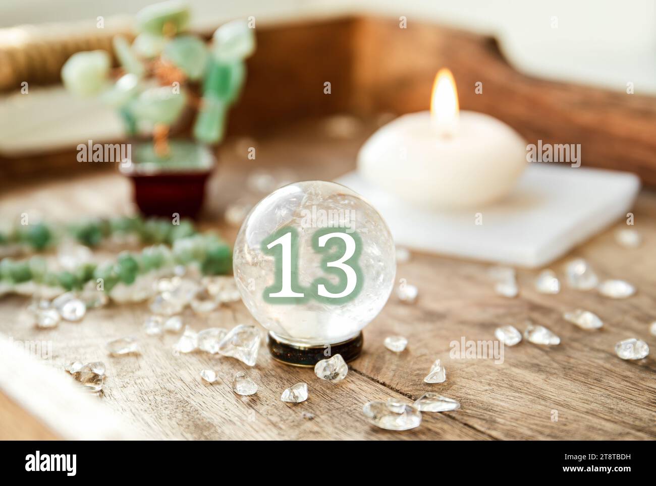Numero tredici sulla sfera di pietra preziosa o sfere di cristallo note come Crystallum orbis e orbuculum. Palla di quarzo naturale trasparente su supporto su vassoio di legno in casa. Foto Stock