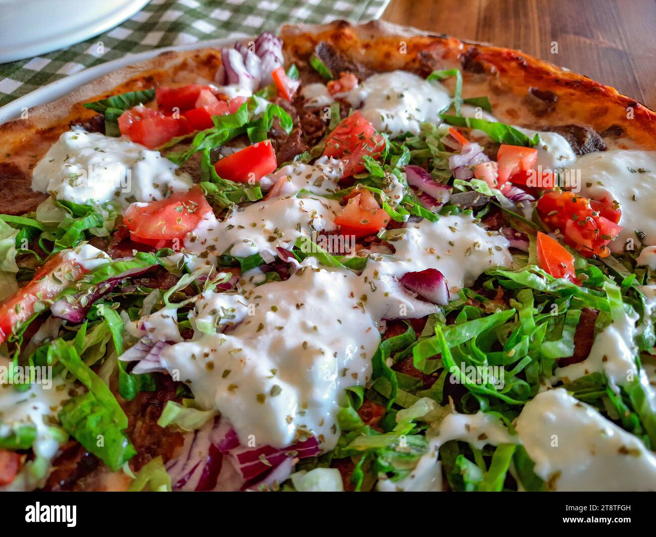 Pizza con pomodori di carne, cipolle e yogurt, primo piano, messa a fuoco selettiva. Foto Stock