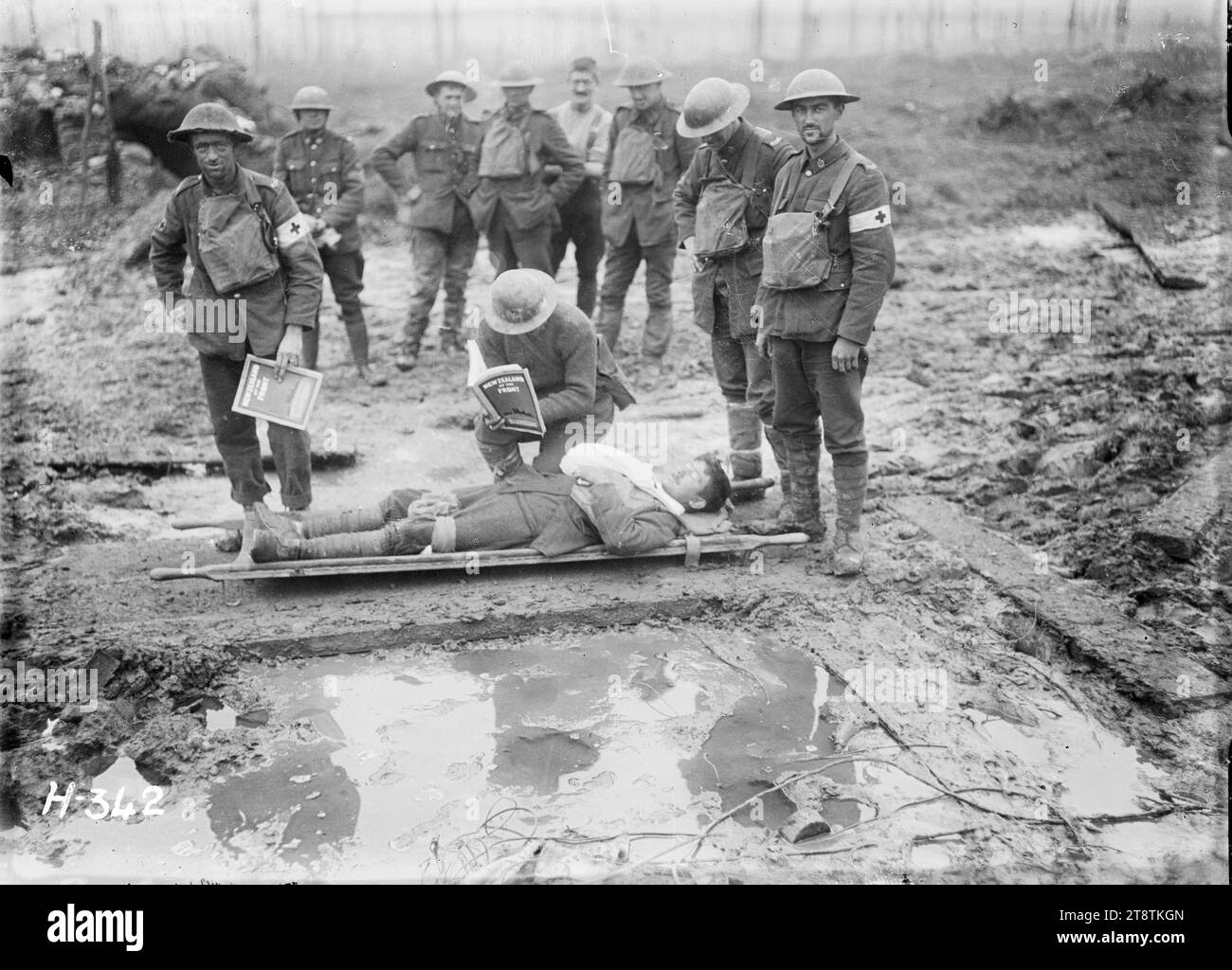 Soldati della prima guerra mondiale del 3° Battaglione, New Zealand Rifle Brigade, a Clapham Junction, Belgio, soldati della prima guerra mondiale del 3° Battaglione, New Zealand Rifle Brigade, in condizioni fangose a 'Clapham Junction', Belgio. Mostra una battuta di lettura dalla pubblicazione 'NZ at the Front' a un uomo ferito su una barella. Fotografia scattata intorno al 20 novembre 1917 Foto Stock