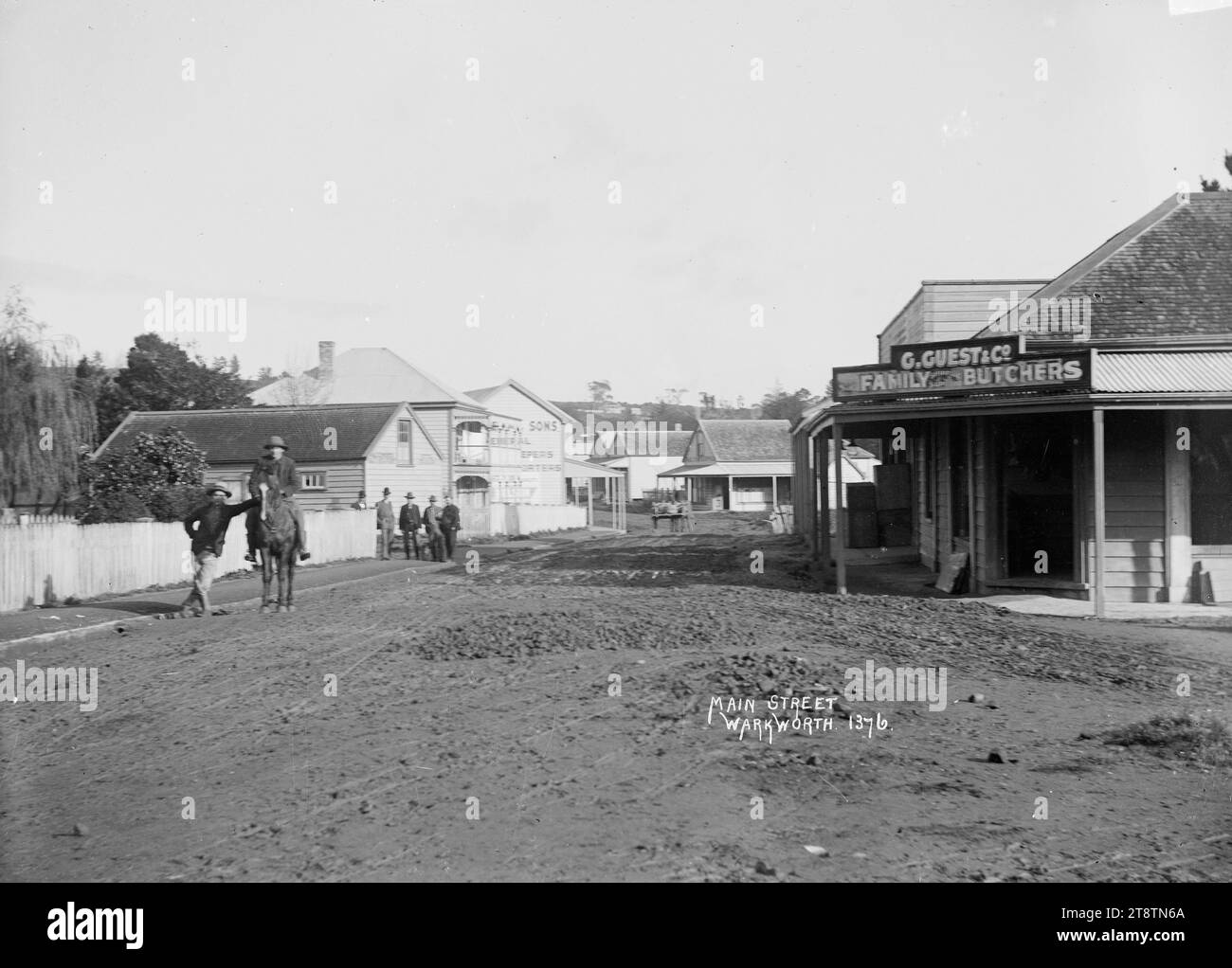 Main Street, Warkworth, mostra la strada principale di Warkworth con un uomo a cavallo e alcuni uomini in giro. Sulla destra si trova il business di G Guest & Co, macelleria per famiglie. Si possono vedere altri punti vendita. all'inizio degli anni '1900 Foto Stock