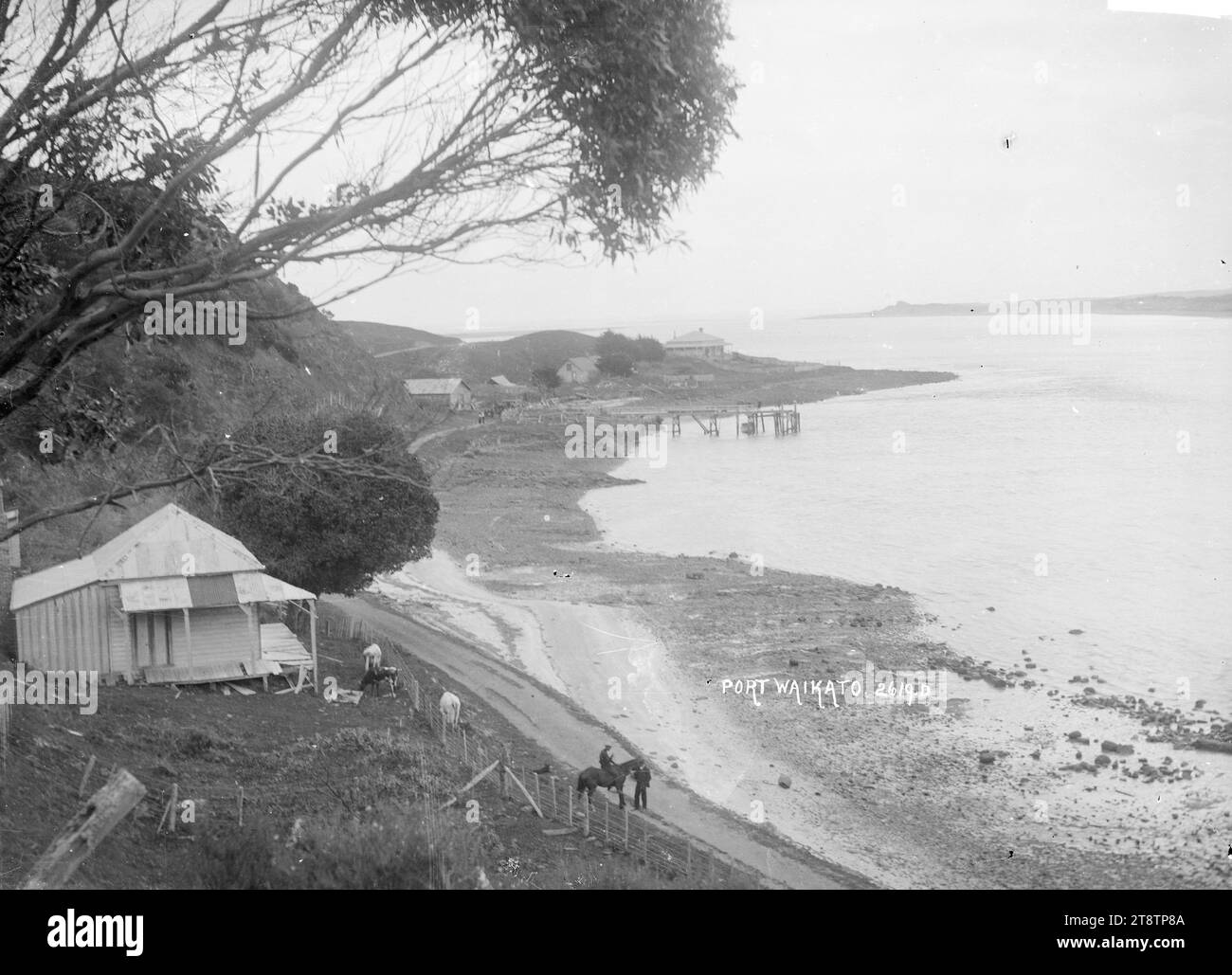 Scena sul lungomare di Port Waikato, scena sul lungomare di Port Waikato, con spiaggia, strada, molo, edifici, e una casa in primo piano a destra. P tra 1910 e 1930 Foto Stock