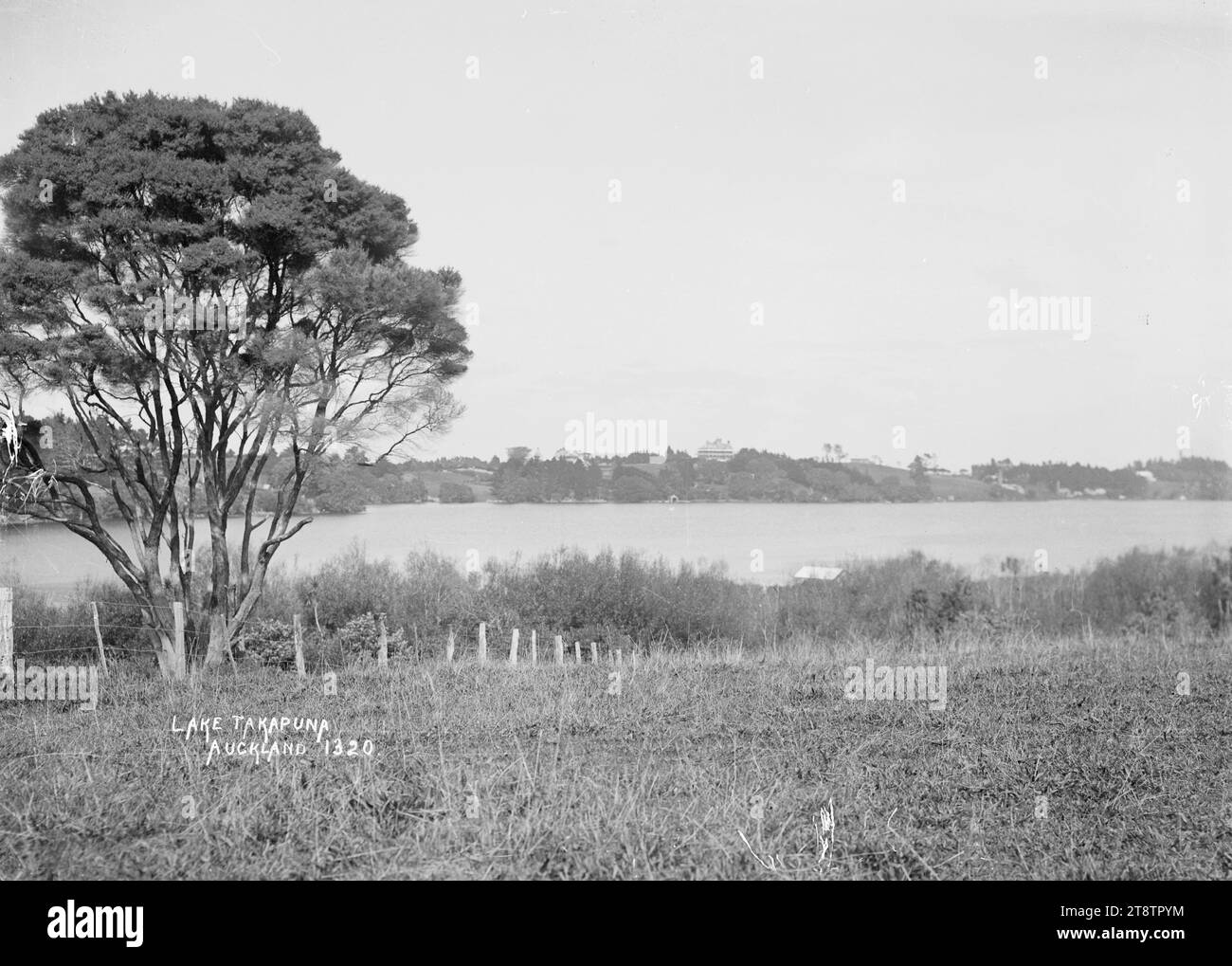 Vista del lago Takapuna, Takapuna, vista sul lago Takapuna (ora noto come lago Pupuke) dal lato opposto. Il Lake Hotel in Killarney Street e la casa di Sir Henry Brett in Killarney Street possono essere visti all'orizzonte Foto Stock