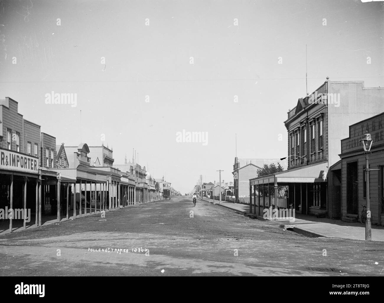 Guardando in Pollen Street, Tamigi, guardate in giù Pollen Street con la macelleria di famiglia di William Taylor (con veranda al secondo piano) in lontananza sulla sinistra. Altre aziende identificabili sul lato destro sono J Paul, saddler e F Shaw, bootmaker. Nell'immediato primo piano a destra c'è un commerciante di provviste e sul lato opposto della strada c'è un'impresa di importazione. Una donna sta andando in bicicletta verso il fotografo a media distanza. Foto scattata nei primi anni '1900 Foto Stock
