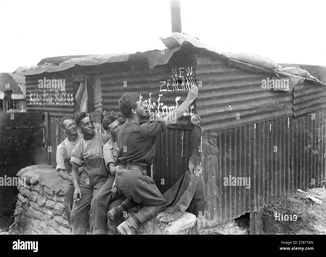 Soldati neozelandesi al campo, prima guerra mondiale, Un soldato neozelandese scrive "nuova Zelanda" all'esterno di un edificio in ferro ondulato a piacere degli altri tre soldati che guardano. Preso durante la prima guerra mondiale Foto Stock